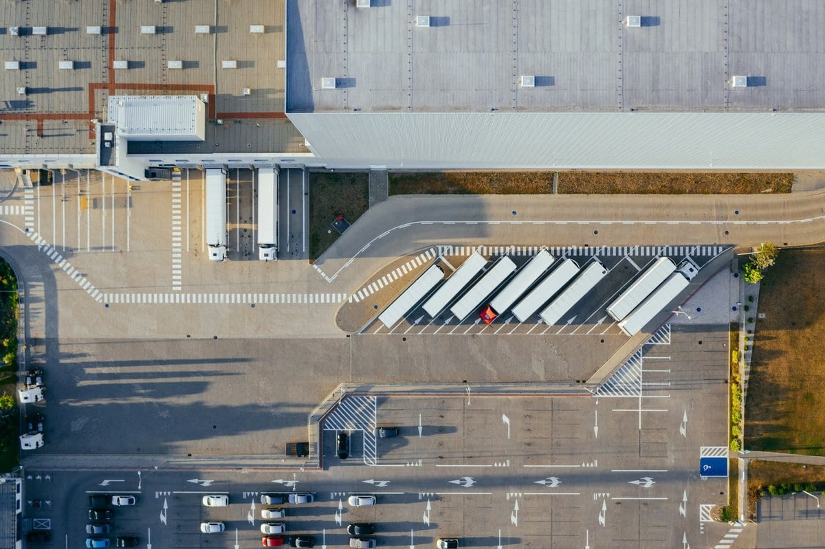An overhead shot of the outside of a warehouse with trucks lining up